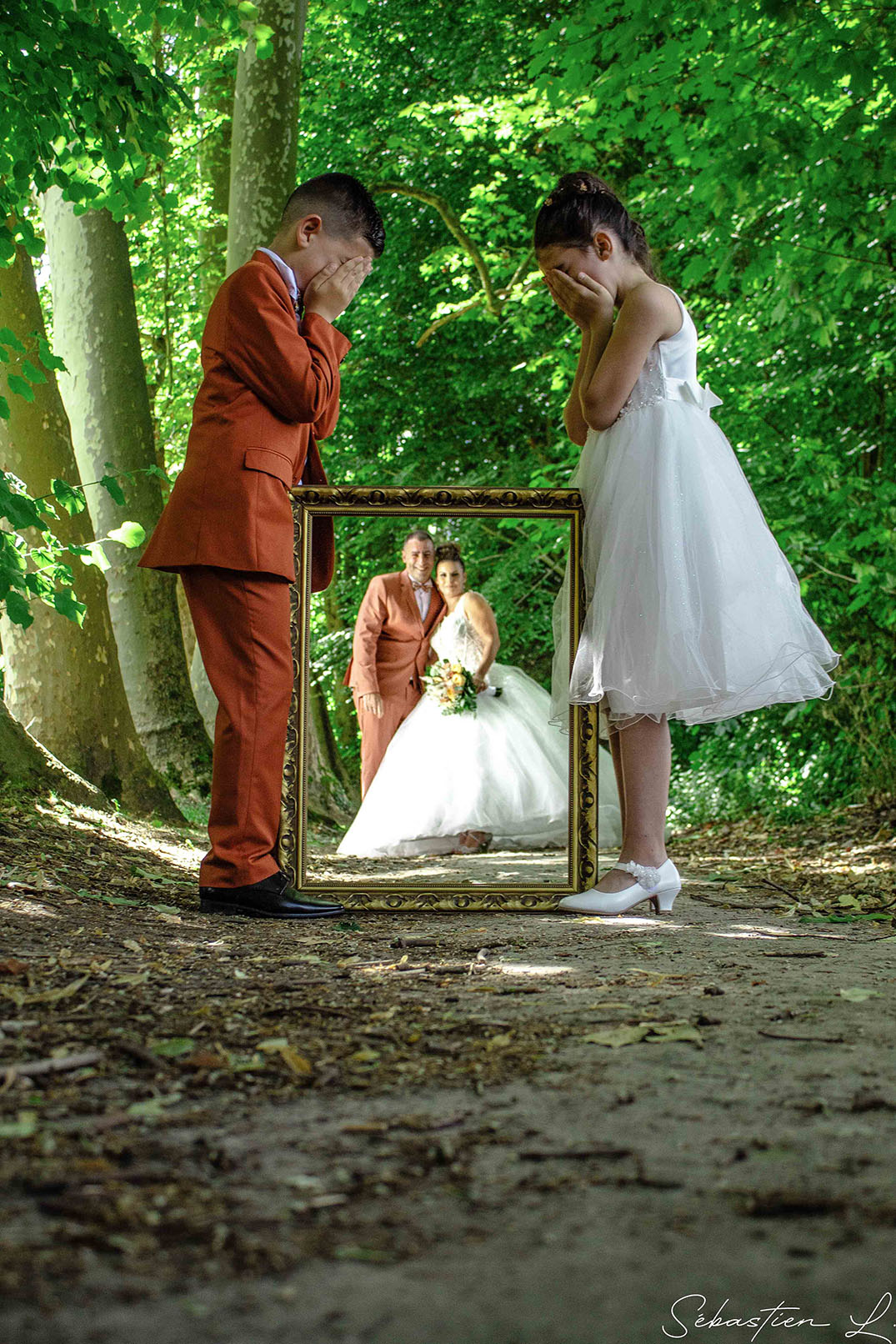 Portraits des mariés à travers un cadre tenu par leurs enfants qui se cachent les yeux Portraits des mariés à travers un cadre tenu par leurs enfants qui se cachent les yeux